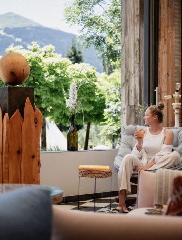 Frau blickt in die Berge mit Drink in der Hand