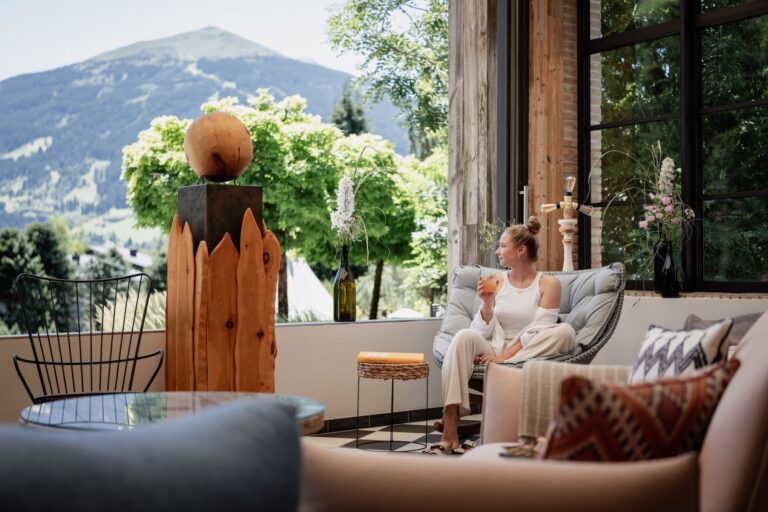 Frau blickt in die Berge mit Drink in der Hand